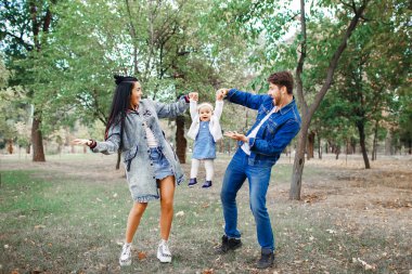 Aile parkta yürüyor, annesi küçük kızınız başını tutuyor, babası ailesine bakıyor