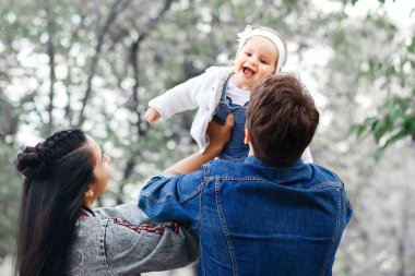 Mutlu aile açık havada etkinlik, baba bebek, gülüyor yükseltir ve oynarken, baba anne gösteren nasıl atar Bebek güvenliği için