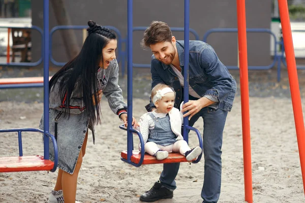 Beaux jeunes parents, marcher avec un enfant, le balancer sur une balançoire, s'amuser et profiter les uns des autres, famille heureuse pour une promenade — Photo