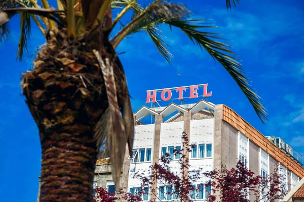 Hotel no fundo de palmeiras, um grande sinal, o conceito de uma viagem turística, uma bela vista do edifício — Fotografia de Stock