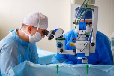 İki göz doktoru ameliyathanede bir operasyon, göz lerle hassas çalışma, göz ameliyatı, iki bilim adamı mikroskoplardan bakıyor