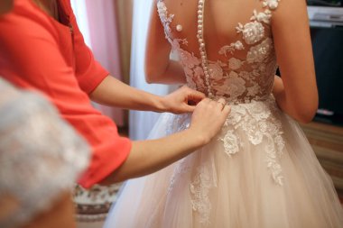 Gelin beyaz dantelli bir gelinlik giyer gelinin annesi ve kız arkadaşı elbiseyi arkadan bağlamaya yardım eder. Düğün günü. Damatla tanışmaya hazırlanıyorum.