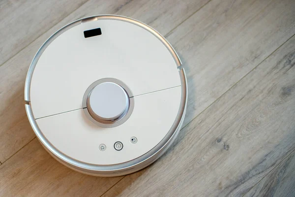 a robot vacuum cleaner on a laminate, cleaning a wooden floor, smart technologies, cleaning a house without the help of the owner, cleanliness without any effort
