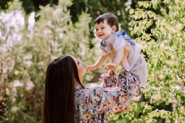 Anne bir yaşında oğlunu kollarında tutuyor, güzel bir akşam ışığı, aile eğleniyor, anne-çocuk ilişkileri, annelik mutluluğu, genç kadın, babasız aile.