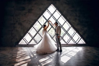 Gelin ve damat arka planda dans ediyorlar, yeni evliler düğün gününde eğleniyorlar, güzel bir gelinlik, karı koca arasında tutku ve şefkat.