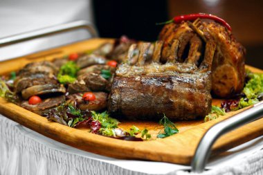 Ateşle pişirilmiş ahşap tepside çeşitli etler, salata ve acı biberli biftekler, bir restoran yemeği, kütüklerin arka planı, büyük bir şirket için bir sürü et, mesaj atılacak bir yer.