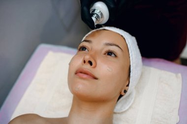 Yüz maskesi soymak, kaplıca tedavisi, cilt bakımı. Spa salonunda estetik ameliyatı olan bir kadın, genç bir kızın yüzüne maske takan usta bir güzellik uzmanı, yazı için yer, yatay fotoğraf.