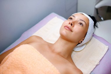 Güzeller güzeli genç bir kadın kaplıcada kozmetik ameliyatlara hazırlanıyor. Güzellik uzmanı genç bir kızın yüzüne bir maske takacak. Yazı için yer, yatay fotoğraf.