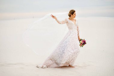 Beyaz desenli gelinlik içinde güzel bukleli sarışın bir gelin çölde yürür, düğün gününde, bir kadın eliyle bir peçe tutar, mesaj atacağı bir yer, damatla buluşmaya gider.