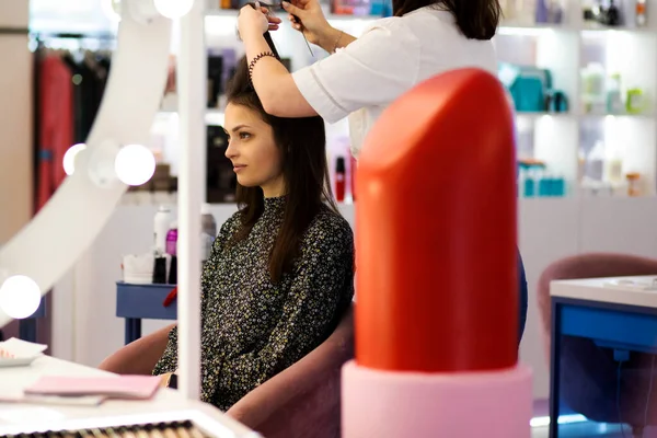 女性のサロンの若い女性は 美容師のサービスを使用し ファッショナブルな髪型のために彼女の髪を編み プロの美容師はブルネットと仕事 テキストのためのフリースペース — ストック写真