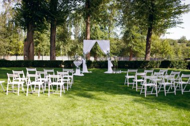 Doğal çiçeklerle süslenmiş bir düğün kemeri ormandaki yeşil bir çimenlikte duruyor. Gelin ve damadın buluşması için her şey hazır. Yeni evliler için güzel bir düğün dekoru. Metin için yer