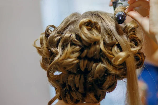 Curlers make curls on women\'s hair. Hairdresser services for the concept of evening and festive hairstyles. Close-up curls and curling iron that makes them