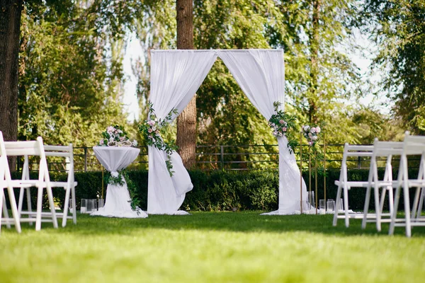 一个装饰着自然花朵的婚礼拱门矗立在森林的绿色草坪上 一切都准备好迎接新郎新娘的到来了 一个为新婚夫妇准备的漂亮的婚礼 — 图库照片