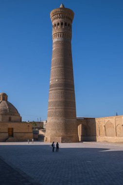 Kalon 'un büyük minaresi. Yoldan minareye bak. Orta Asya 'da eski bir bina. Buhara Özbekistan 'da büyük bir minare. Orta Asya 'da yaz güneşli bir gün.