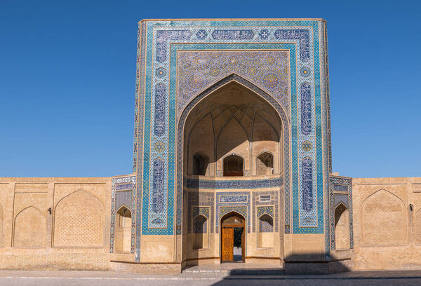 The Kalyan mosque in Bukhara, Uzbekistan. View of the mosque in the ensemble Po-I-Kalyan. Ancient building in Central Asia on a Sunny day. View of the open door with a tree in the yard.