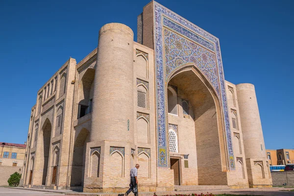 Nadir Divanbegi Khanaka 'nın aşağıdan sağa ve aşağıdan geçen bir adamla görüntüsü. Özbekistan, Buhara 'daki eski bir binanın manzarası. Nodir Devonbegi xonaqohi, Orta Asya 'da güneşli bir yaz gününde.