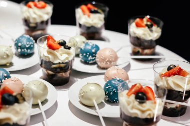 Krem şantili ve beyaz bir masada çilekli tatlılar. Büyüleyici bir stil