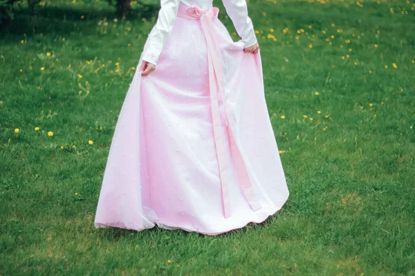 Çimlerin üzerinde pembe gelinlikli bir kız.
