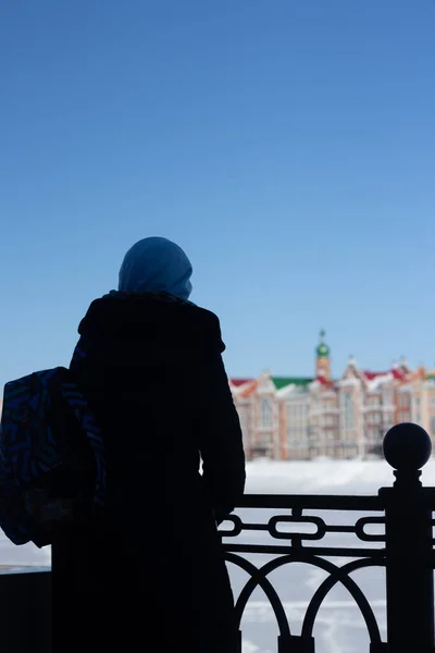 Waterfront houses in the city of Yoshkar-Ola, in Russia. Winter snow. Sights of the city of Yoshkar-Ola. Colorful houses. Muslim traveler with a backpack looks at the city.