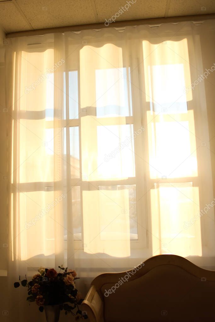 Window silhouette on the curtains. Rays of sunshine through a white curtain.