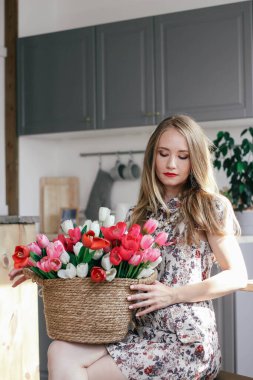 Mutfakta bir sepet lalesi olan sarışın kız.