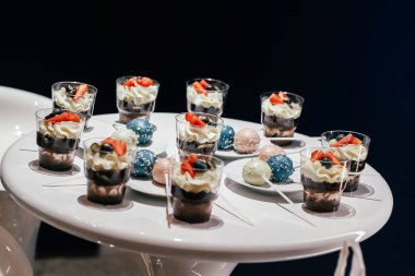 Krem şantili ve beyaz bir masada çilekli tatlılar. Büyüleyici bir stil