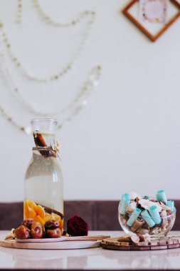 Su portakalları ve tarçınlı süs. Tarihler. Gül çiçeği. Kurumuş çiçekli ve yapraklı bir vazo. İftar, güneş ışığı, hurma ve su. Ramazan