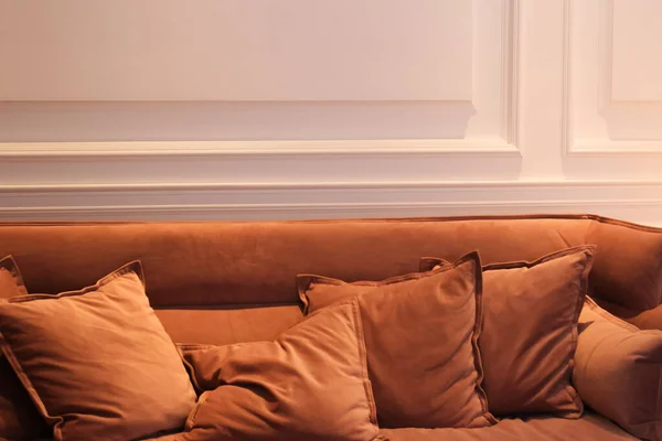 Brown sofa on a white wall background. Pillows on the sofa