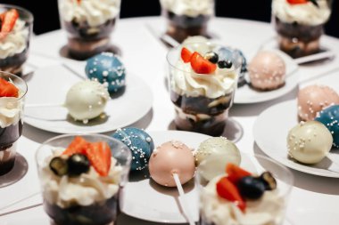 Krem şantili ve beyaz bir masada çilekli tatlılar. Büyüleyici bir stil