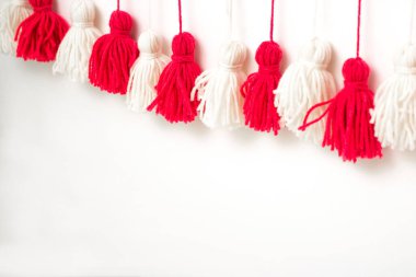 Beyaz arkaplandaki kırmızı ve beyaz ipliklerden fırçalar. İplik fırçaları. Çelenk. İplik çelengi. İplikten Pampushki. Çocukların yaratıcılığı. Planı kapat