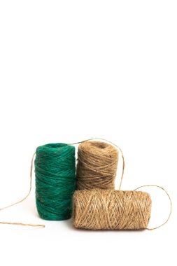 Üç yumak sicim. Tel. Sicim kahverengi ve yeşildir. Beyaz arkaplanda, dizgi