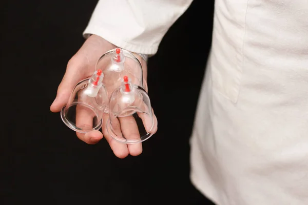 Kavanozlar hijama için, kan alma, siyah arka planda beyaz önlüklü bir doktorun ellerinde. Sunnah 'a göre Hijama. Hajjam