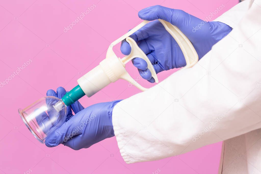 Jars for hijama, oodletting and pumps on the hands of a doctor in a white medical coat on a pink background. Hijama according to the Sunnah. Hajjam