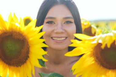Sahada beyaz bluzlu, ayçiçekli güzel esmer kadın. Sarı ayçiçekleri. Planı kapat.