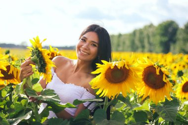 Sahada beyaz bluzlu, ayçiçekli güzel esmer kadın. Sarı ayçiçekleri. Planı kapat.
