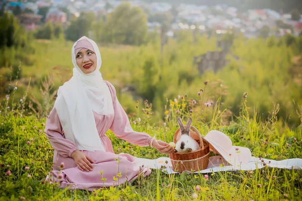 Müslüman Bir Kadın Elinde Tavşan Şapkayla Sepetin Yanında Oturuyor Pembe — Stok fotoğraf