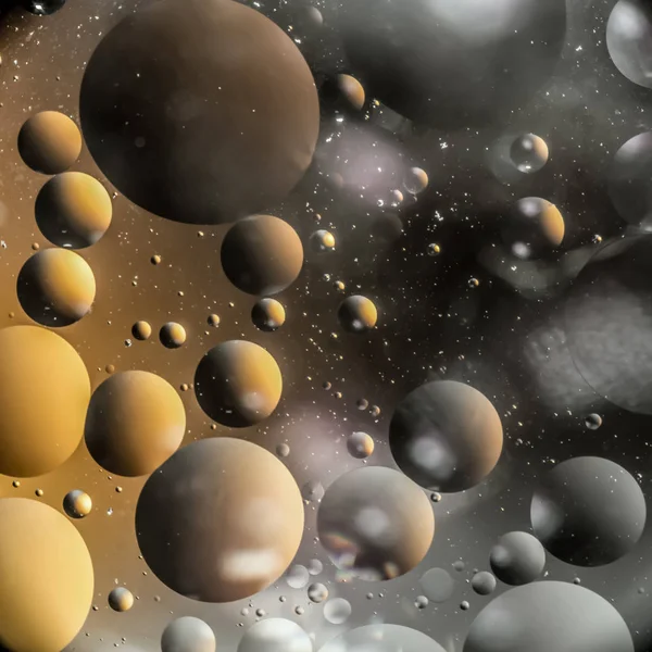 the interaction of water and oil, oil bubbles of various sizes on the water surface, yellow and black abstract macro background with soft defocusing