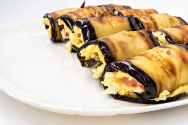 Bir beyaz tabak, yemek yakın çekim arka plan, seçici odak çerçeve merkezinde Patlıcan dolması peynir ve domates yalan dan rulo