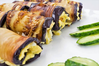 Peynir Rulo gelen Patlıcan dolması, domates ve dilimlenmiş yeşil salatalık yalan bir beyaz tabak, yemek yakın çekim arka plan, çerçeve merkezinde seçici odak