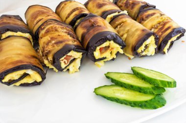 Peynir Rulo gelen Patlıcan dolması, domates ve dilimlenmiş yeşil salatalık yalan bir beyaz tabak, yemek yakın çekim arka plan, çerçeve merkezinde seçici odak