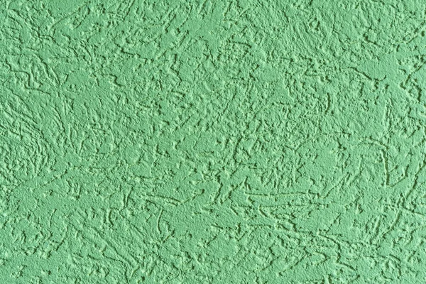 The green texture of the surface of the wall covered with decorative plaster of the woodworm type, close-up architecture abstract background — Stock Image Green Texture Surface Wall Covered Decorative Plaster Woodworm Type Close Stock Photo