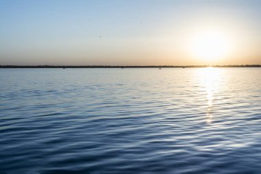 Su yüzey, akşam güneşi defne, yaz gökyüzünde bulutlar olmadan üzerinde üzerinde renkli günbatımı