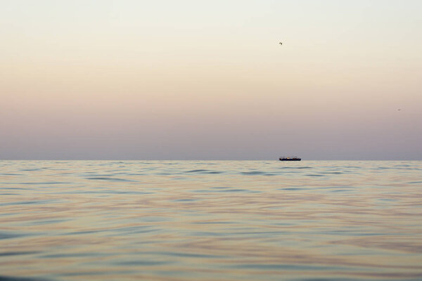 the evening sea with waves, far away on a horizon line floating ship, nature abstract background