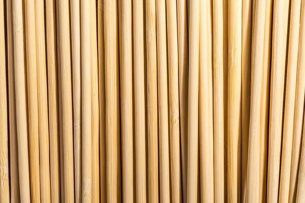 Round wooden sticks background. Wall Pattern. Close-up detail of round wooden sticks wall pattern