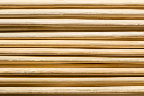 Round wooden sticks background. Wall Pattern. Close-up detail of round wooden sticks wall pattern