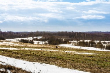 Erken baharda alanlarda kar erime, mavi gökyüzü ve bulutlar ile güneşli bir gün