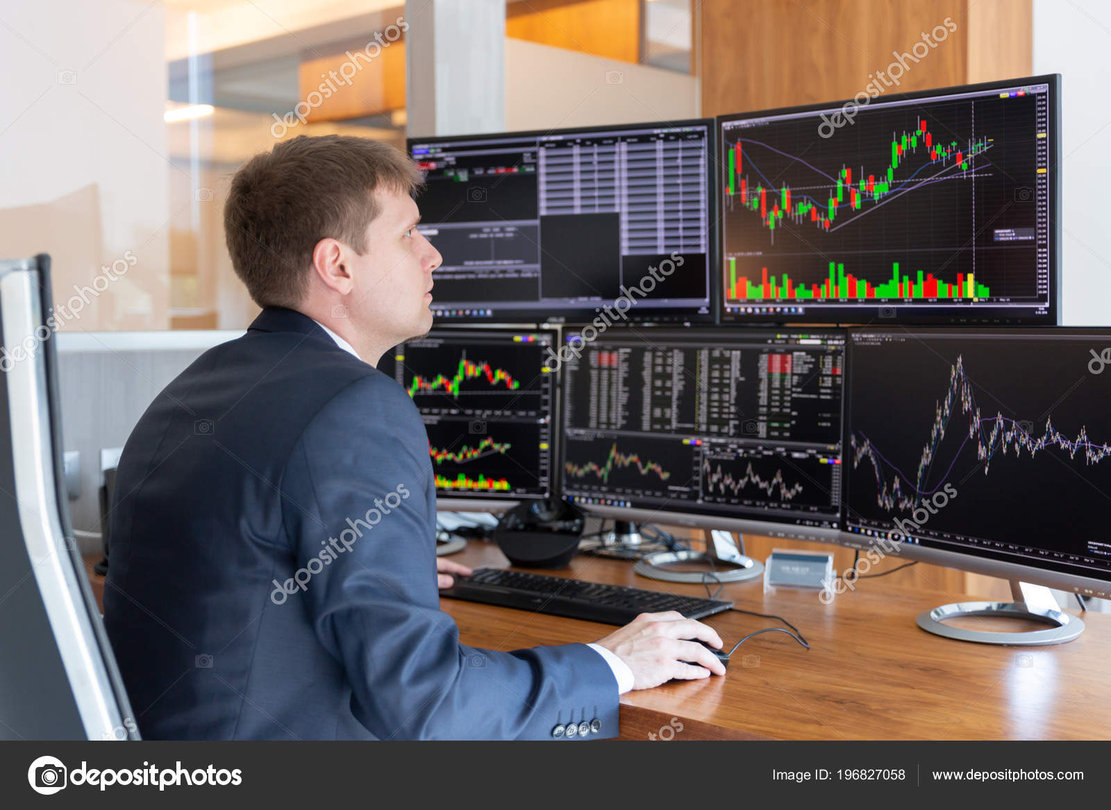 Stock Trader Looking At Computer Screens In Trdading Office