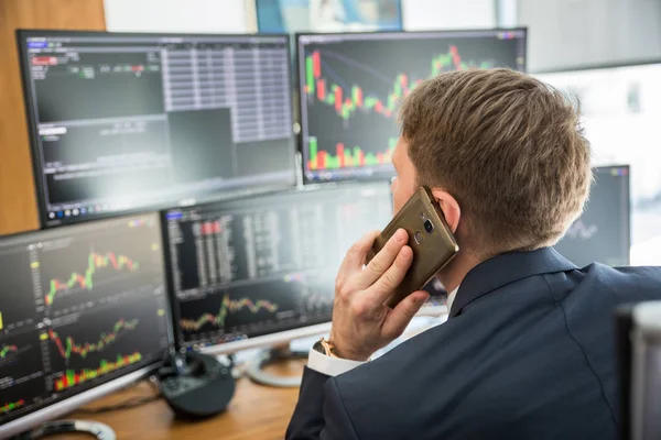 Au-dessus de la vue d'épaule de courtier en valeurs mobilières trading en ligne, parler sur téléphone mobile. — Photo