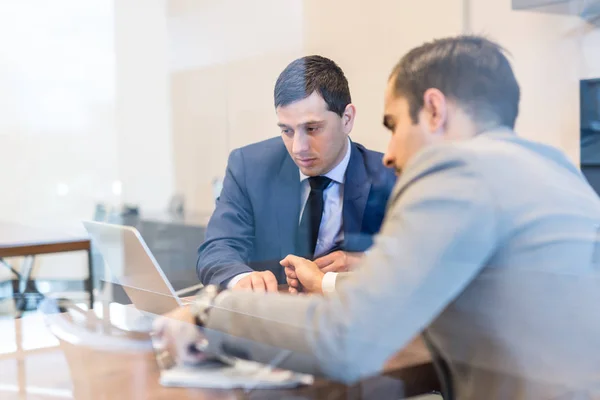 Dois jovens empresários usando computador portátil em reunião de negócios . — Fotografia de Stock