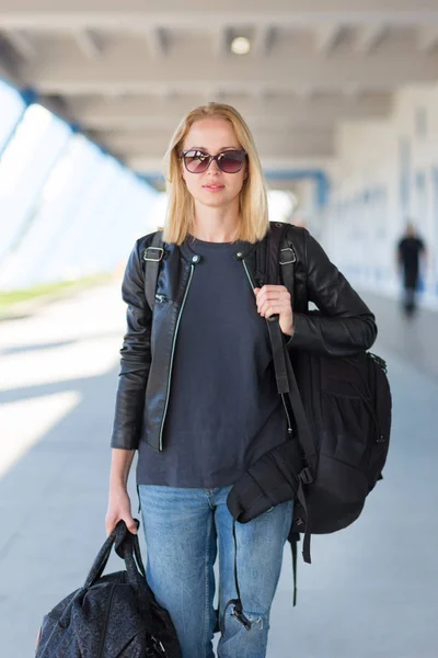 Portré, fiatal vidám nő Traveler visel alkalmi ruhák könyv a nehéz hátizsák és a poggyász repülőtéren. — Stock Fotó